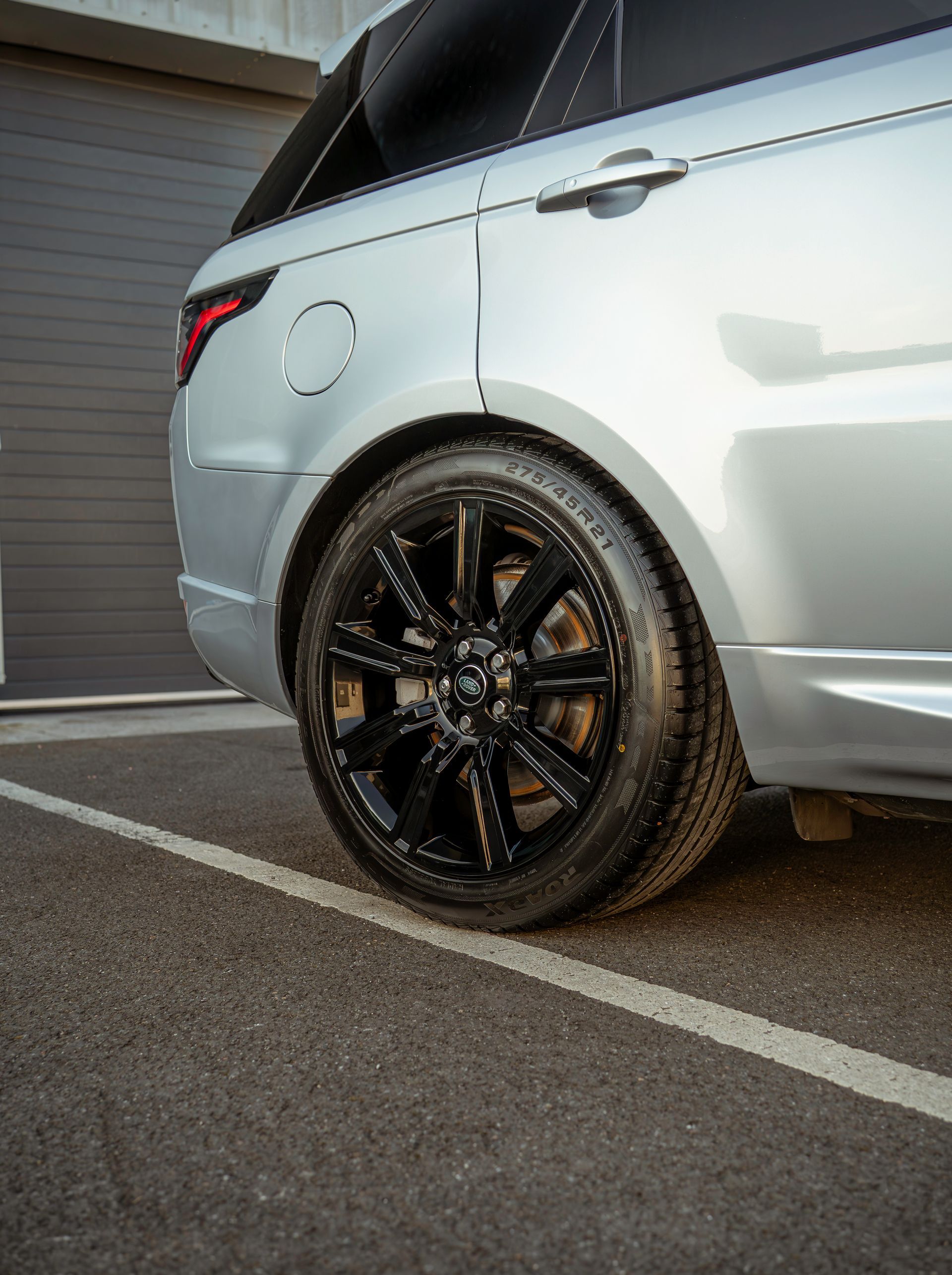 Silver SUV parked on a driveway, showing the rear side and black alloy wheel.