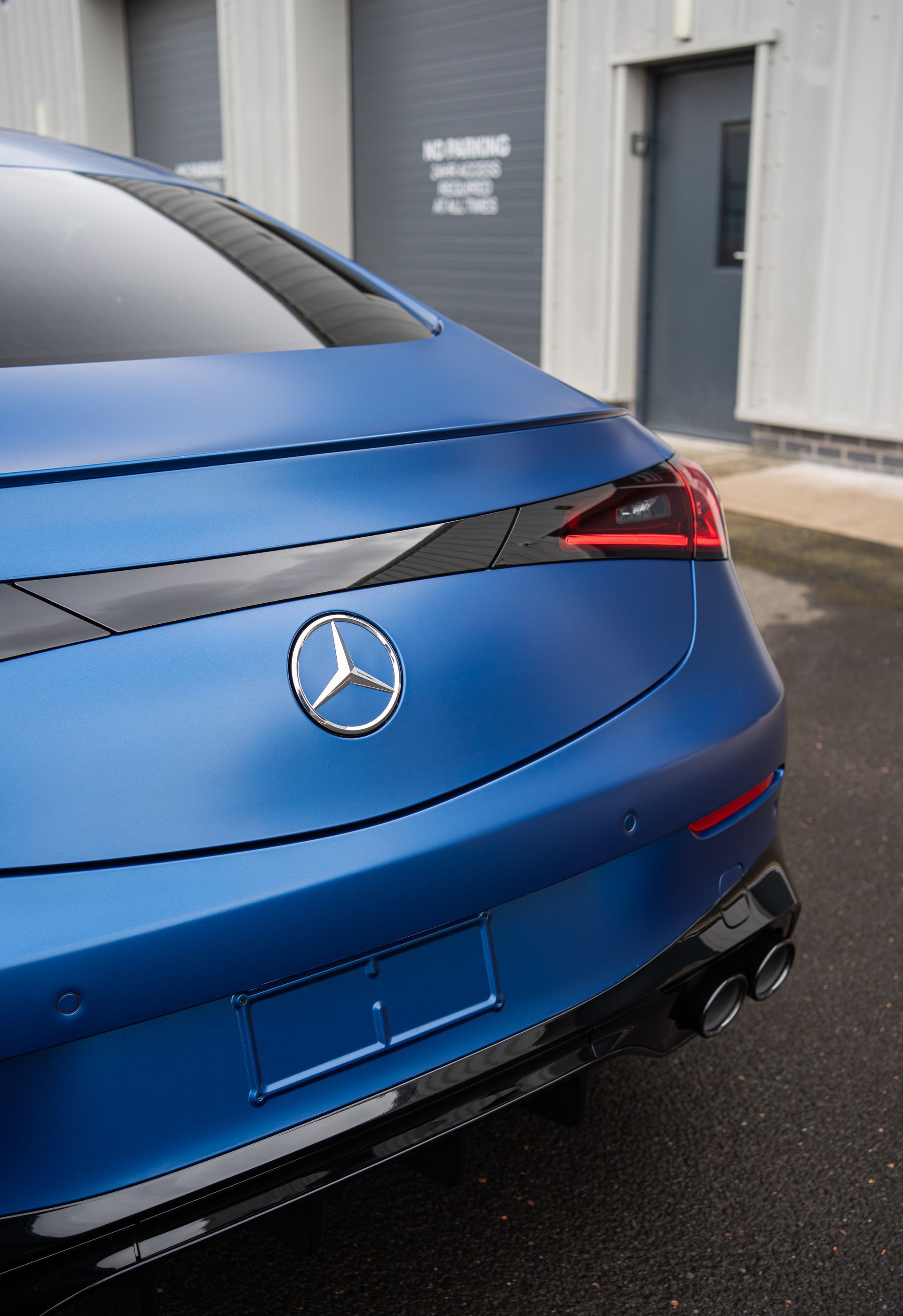 Blue Mercedes-Benz rear parked outside a building on wet pavement