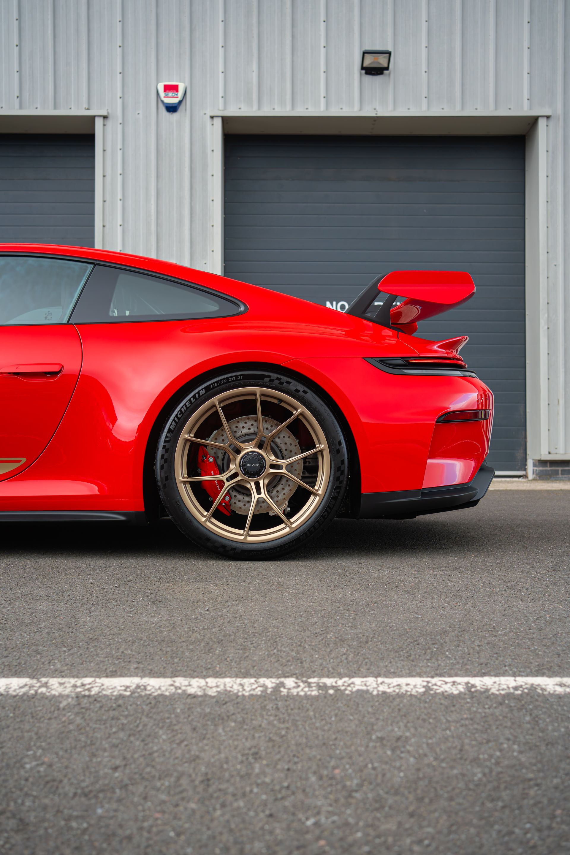 Red sports car parked beside a gray garage door