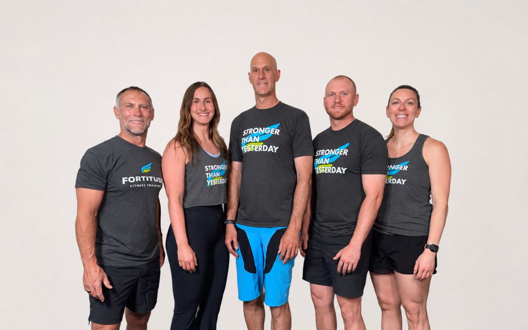 Five adults in matching athletic shirts posing against a plain light background.