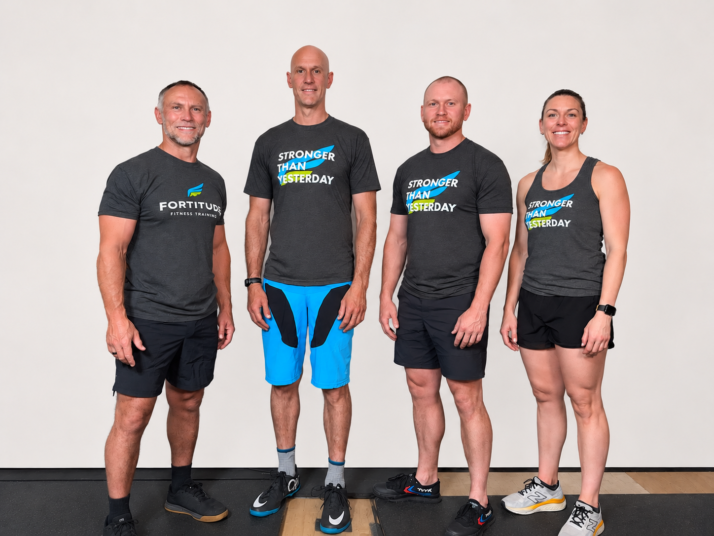 Four adults in matching athletic shirts posing against a plain light background.