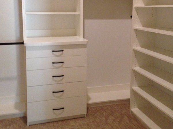 A walk in closet with lots of shelves and drawers