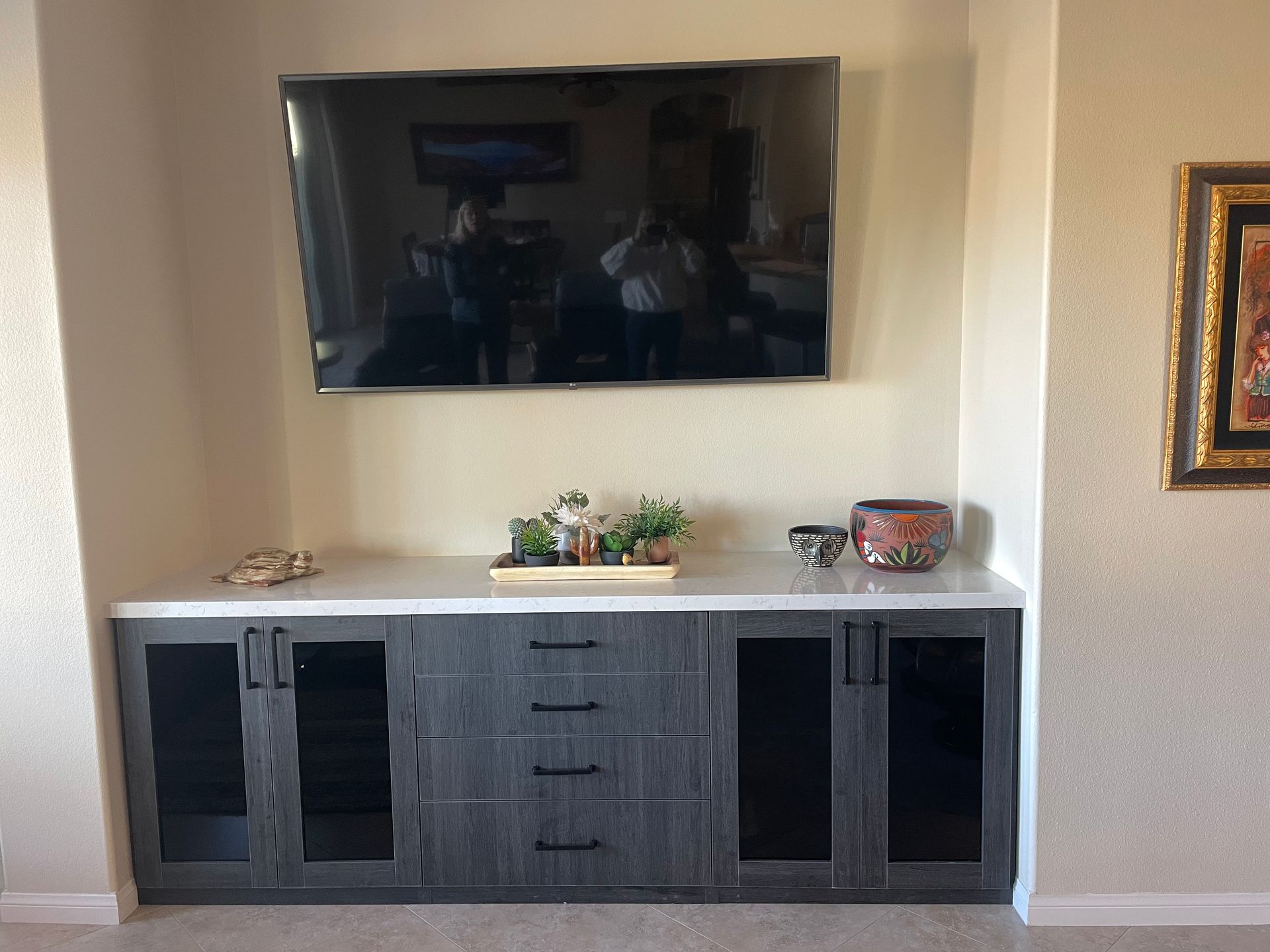 A living room with a flat screen tv mounted on the wall above a dresser.