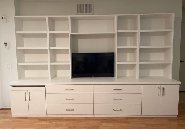 A large white entertainment center with lots of shelves and drawers and a flat screen tv.