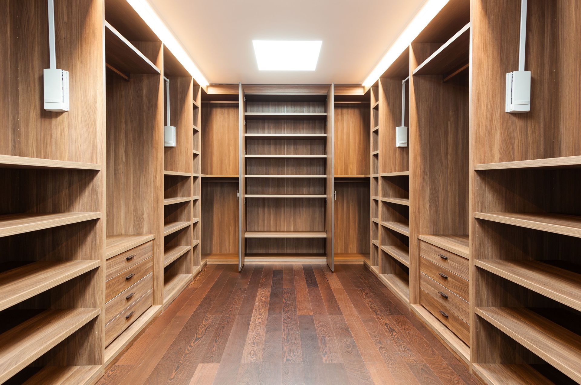 An empty walk in closet with wooden shelves and drawers.