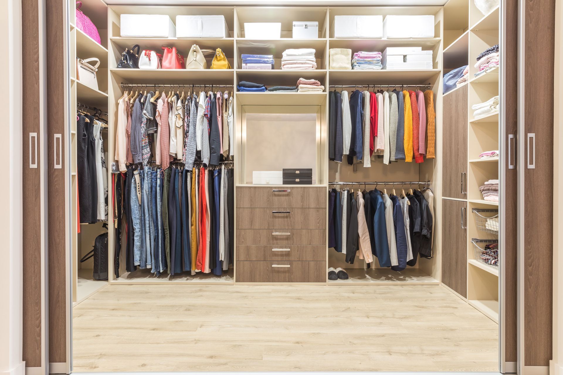 A walk in closet filled with lots of clothes and drawers.