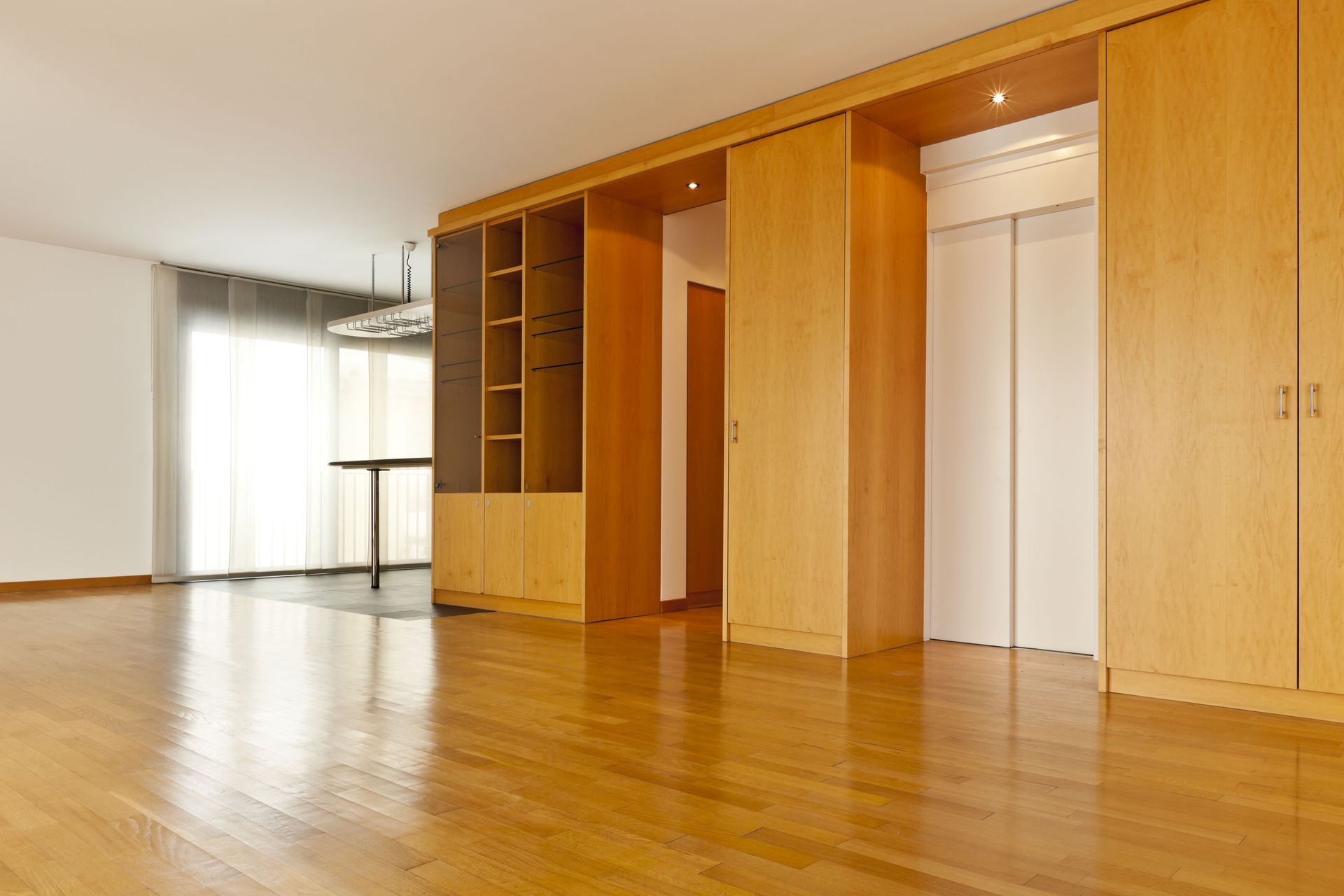 An empty living room with hardwood floors and sliding doors.