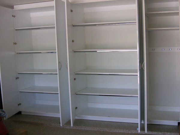 A closet with a lot of shelves and doors open