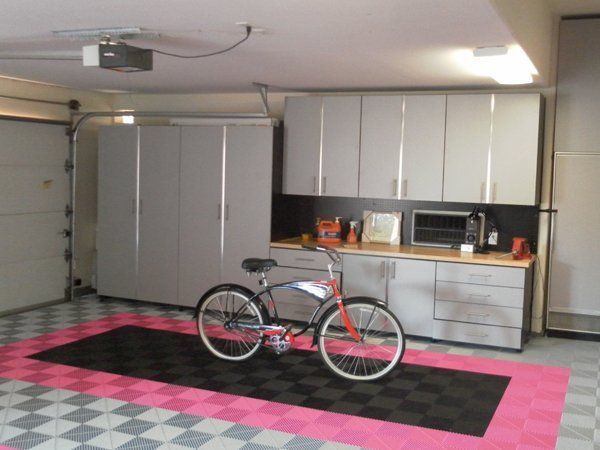 A bicycle is parked on a checkered floor in a garage