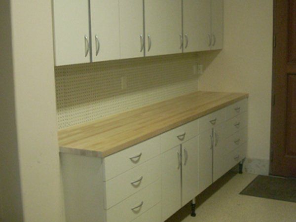 A kitchen with white cabinets and a wooden counter top