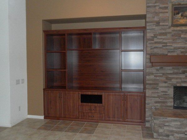 A living room with a stone fireplace and a wooden entertainment center