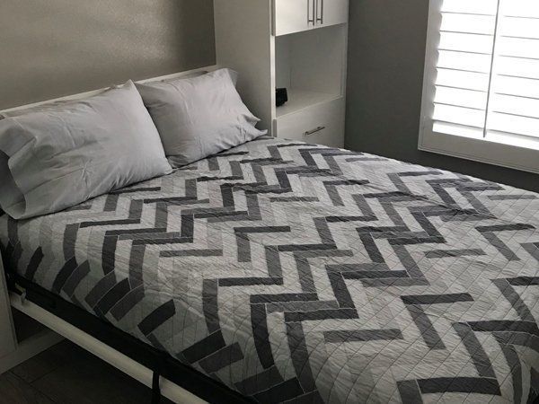 A bed with a chevron patterned blanket and pillows in a bedroom.
