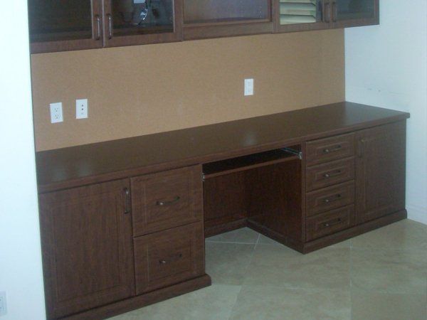 A wooden desk with drawers and cabinets in a room