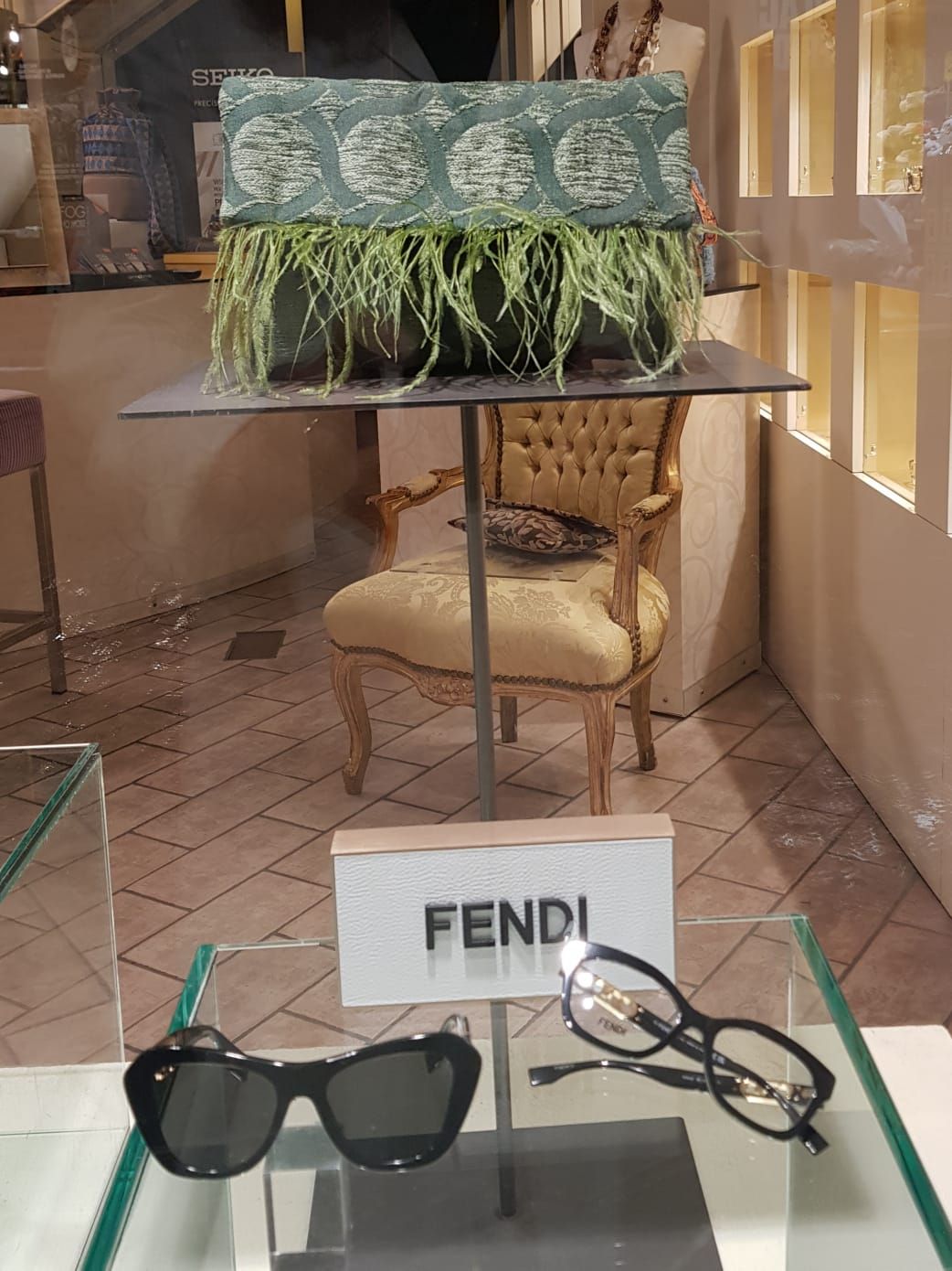 Vetrina Fendi con occhiali da sole e una borsa verde decorativa su un piedistallo