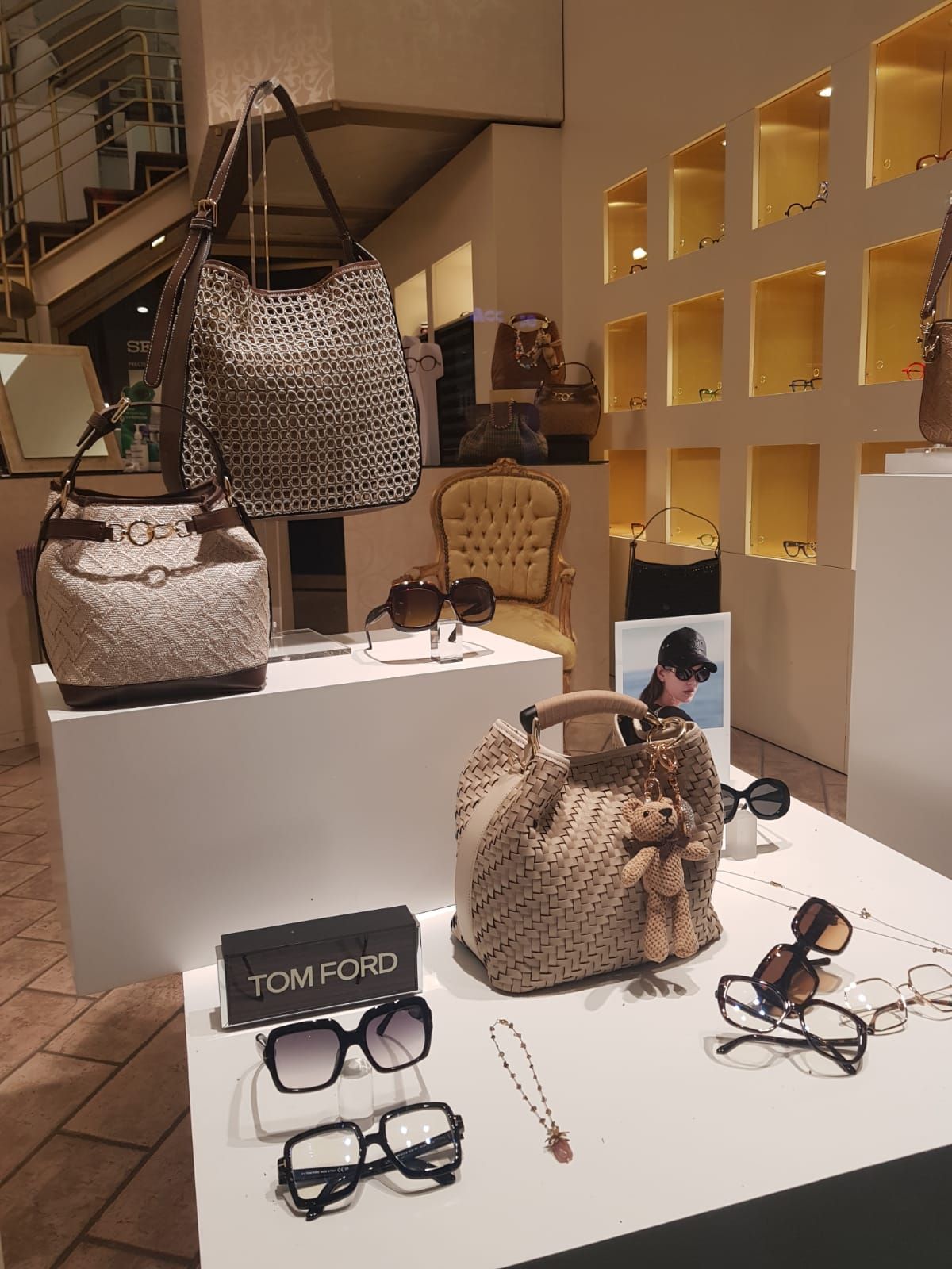 Borse, occhiali e gioielli esposti su piedistalli bianchi in una boutique con luci calde.