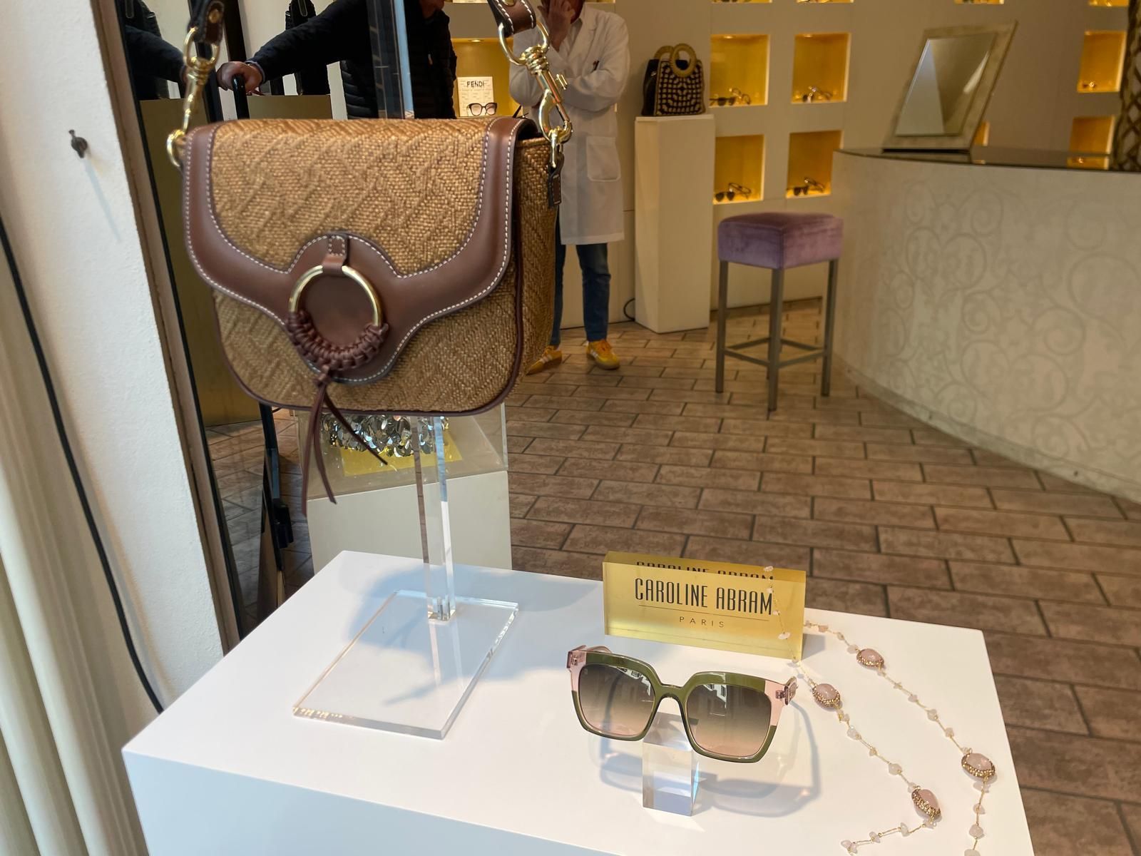 Occhiali da sole e una borsetta con perline esposti su un tavolo bianco in una boutique.