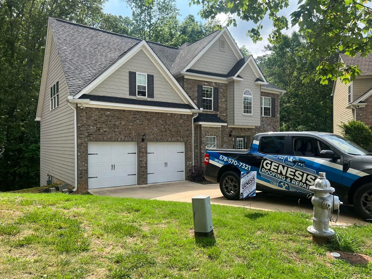 Two-story house with brick and siding, two-car garage, and Genesis vehicle parked on the lawn.