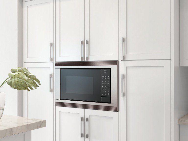 A kitchen with white cabinets and a stainless steel microwave oven.