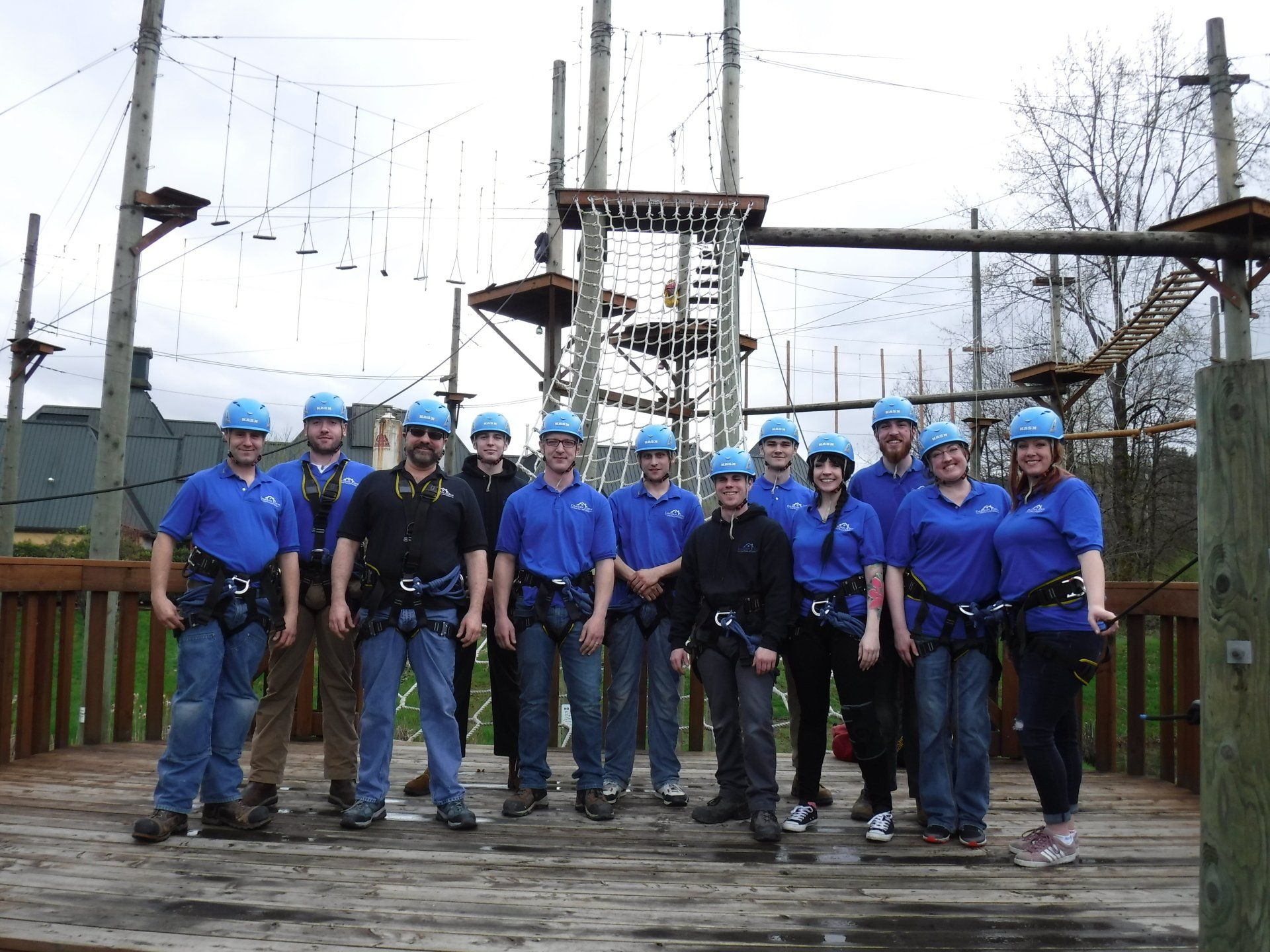 A group of people are posing for a picture in front of a ropes course.