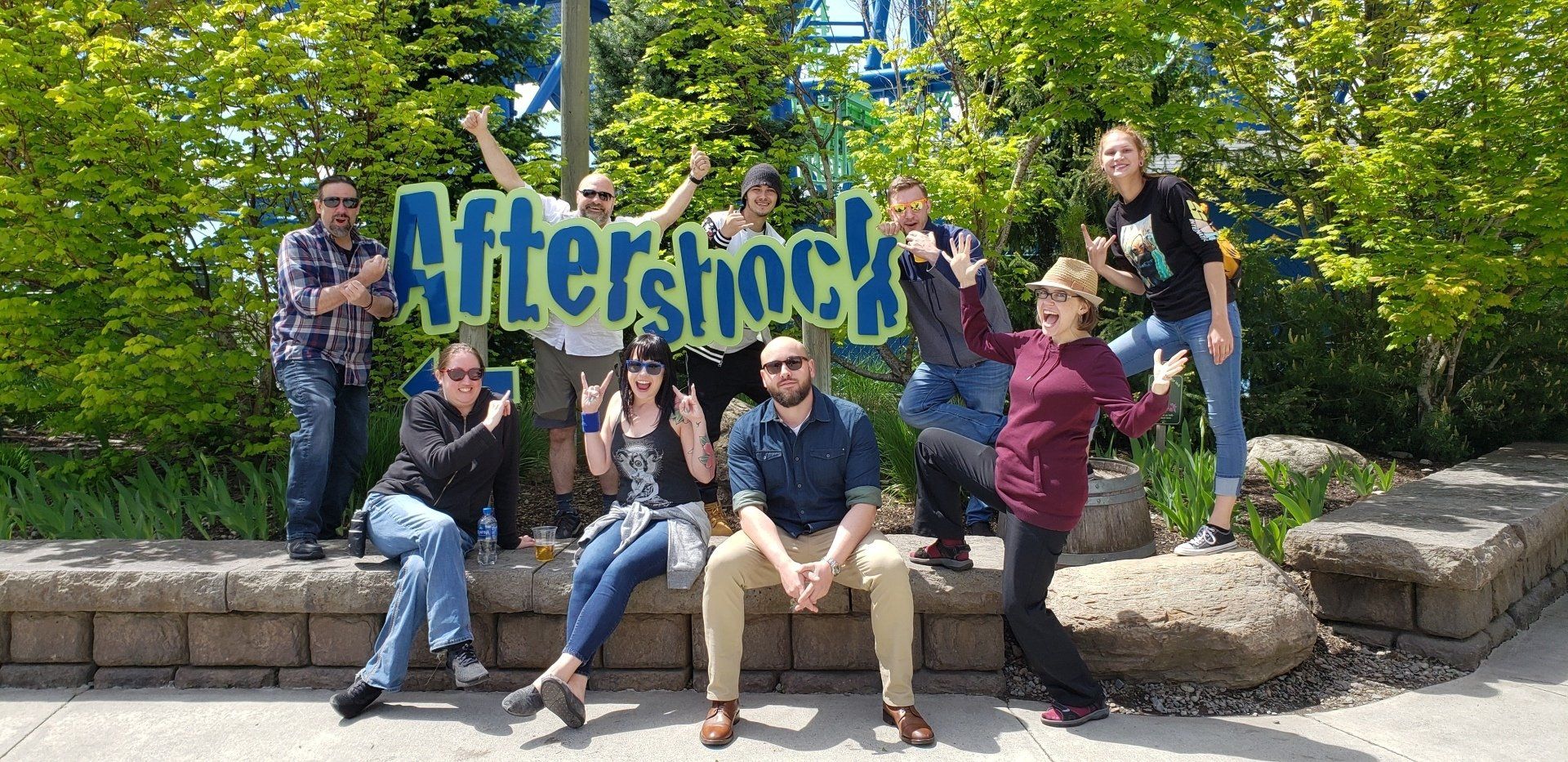 A group of people are posing for a picture in front of a sign that says aftershock.