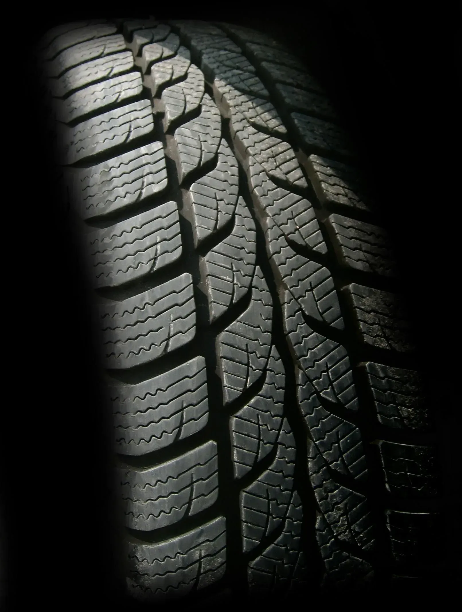 Close-up of a car tire tread on a dark background
