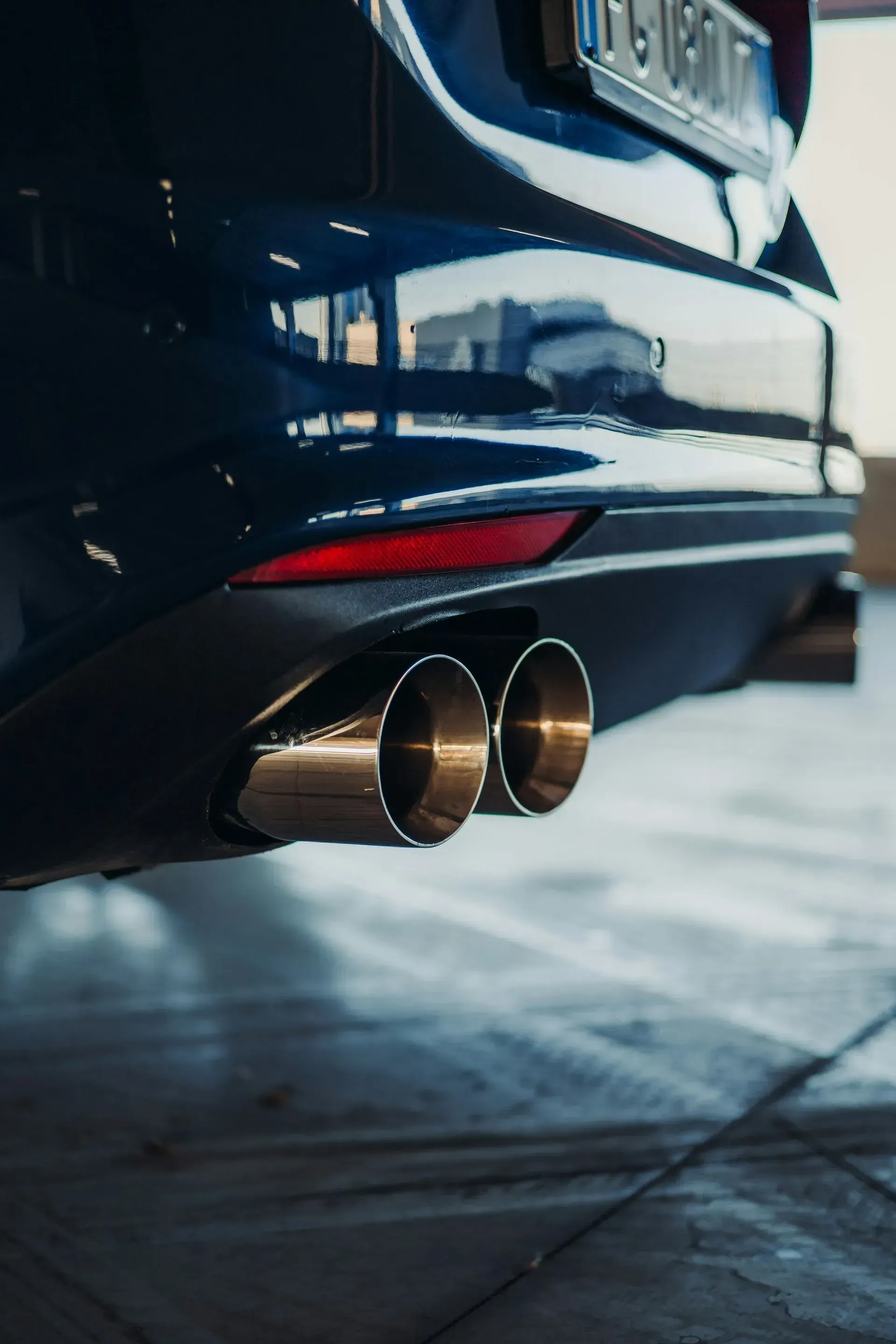 Rear view of a car with dual exhaust pipes over a garage floor