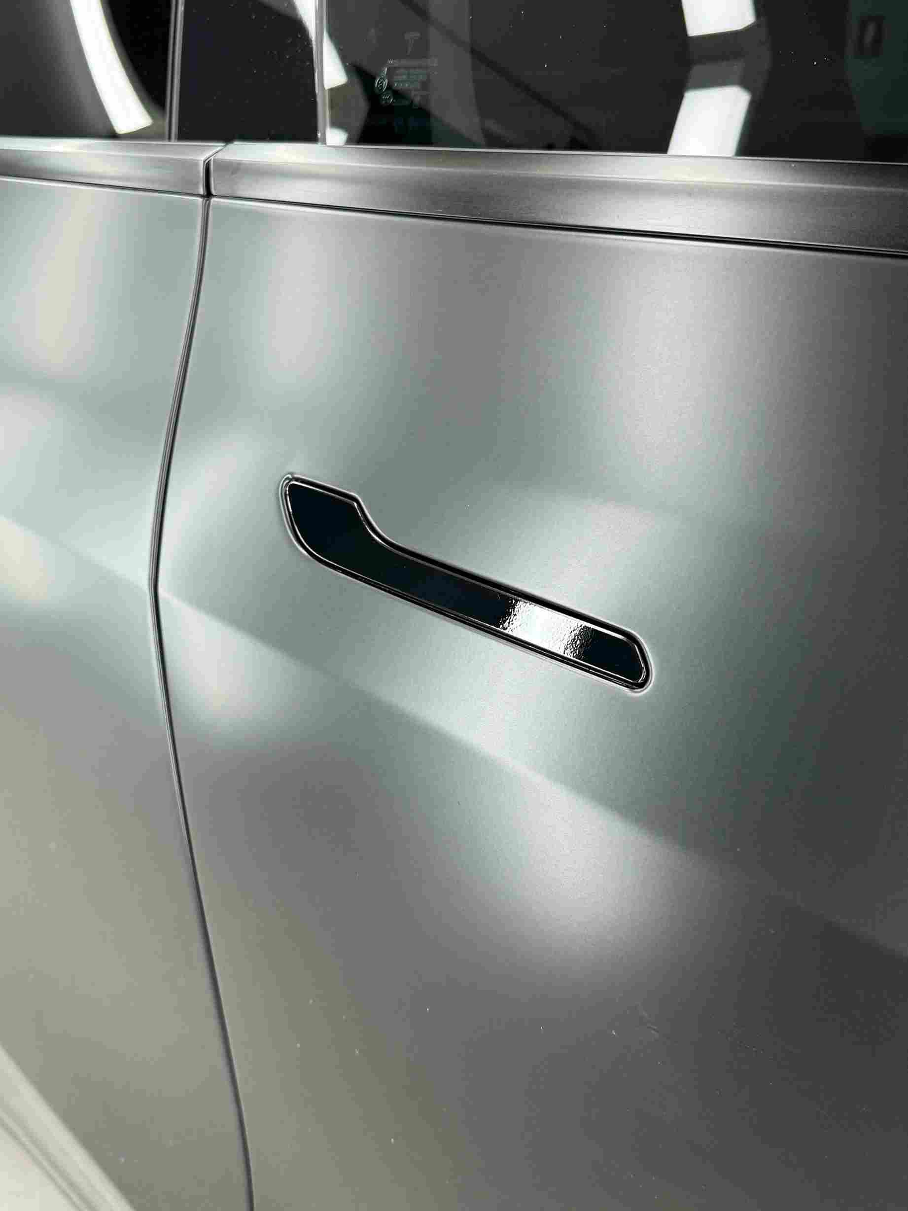 Silver car door with a black handle.