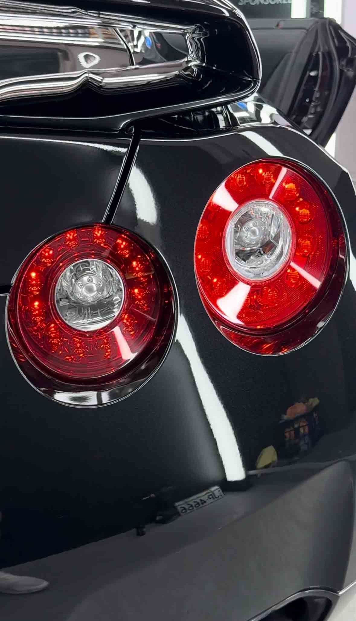 Close-up of a black sports car rear with two circular red taillights.