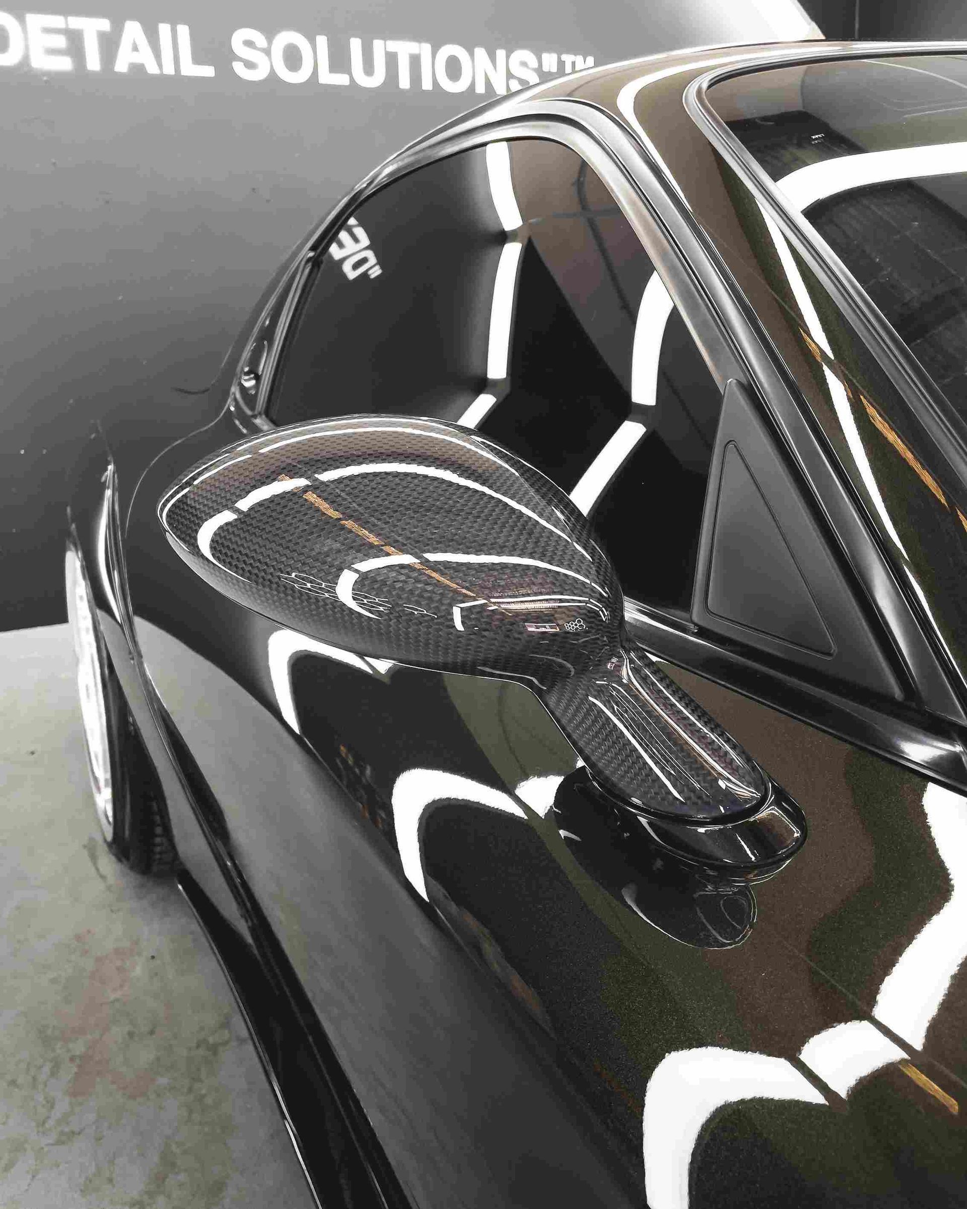Black sports car with carbon fiber side mirror.