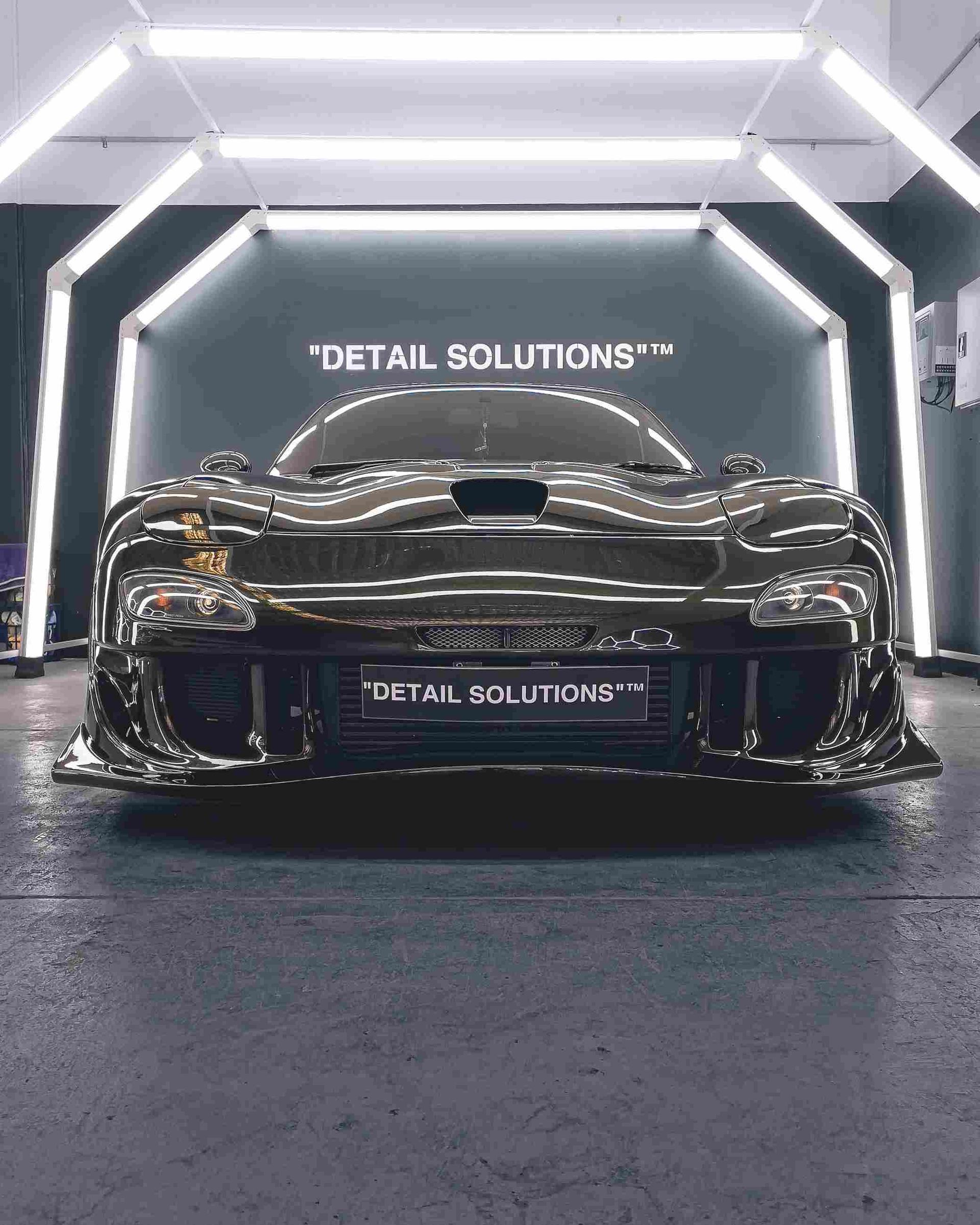 Chrome-plated car under bright lights in a detailing shop.
