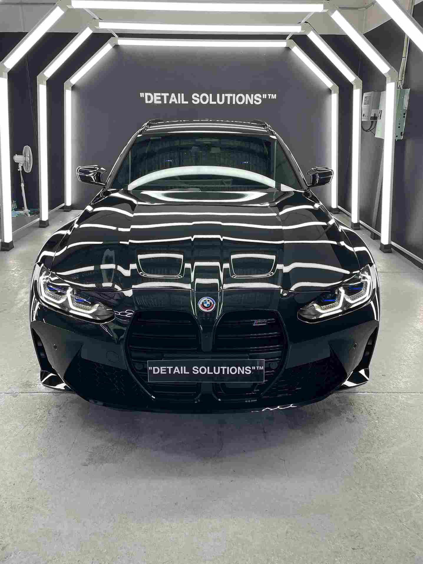 Black BMW car in a detailing shop. Shiny paint, illuminated by lights; 