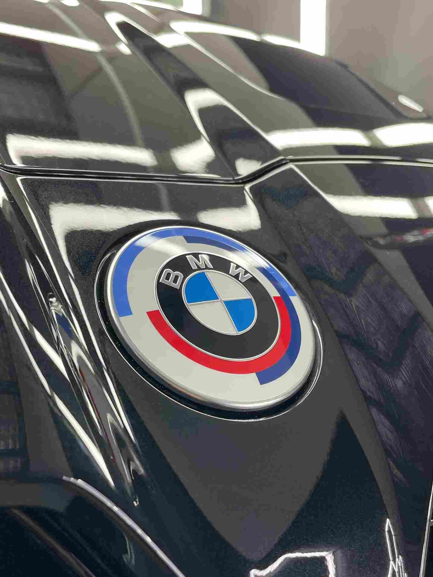 BMW emblem on a shiny black car hood, with blue, red, and white circular design.