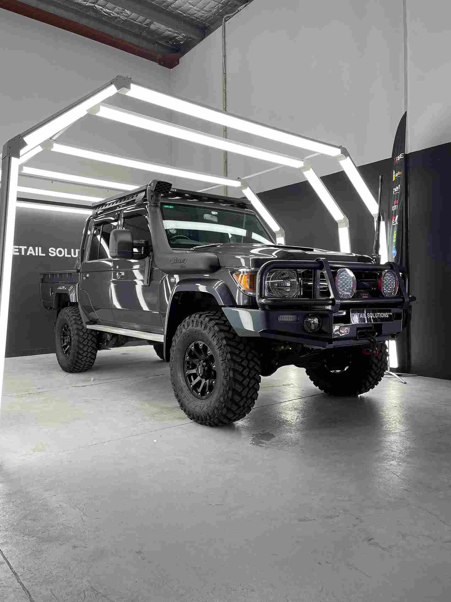 Dark gray lifted Toyota Land Cruiser under bright garage lighting.