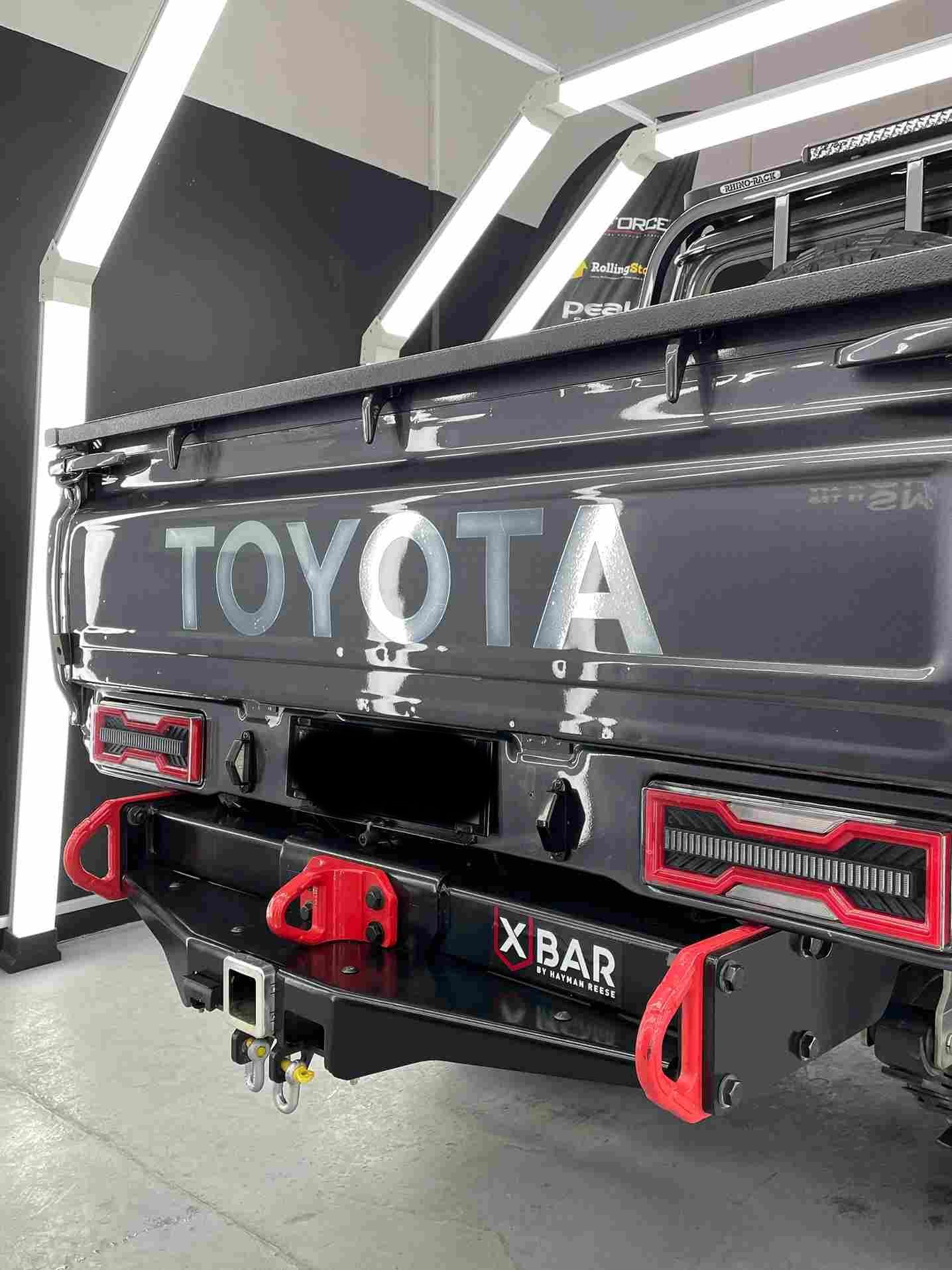 Black Toyota pickup truck rear with X BAR bumper, red accents, and Toyota logo.