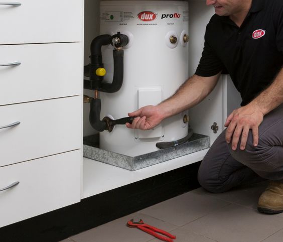 Technician Kneels Beside a White Water Heater — Forster Hotwater in Forster, NSW