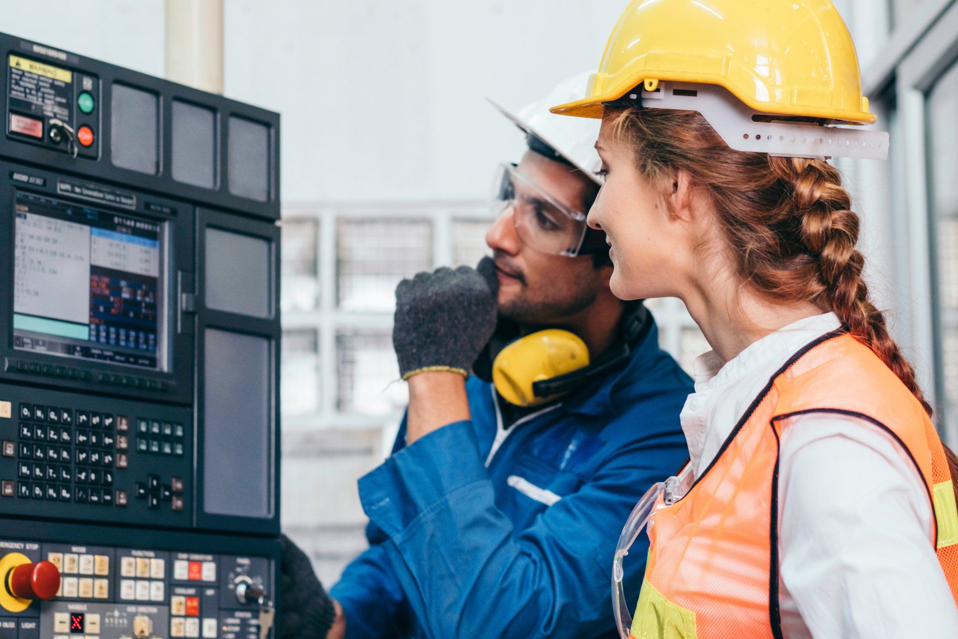 A man and a woman are working on a machine in a factory.