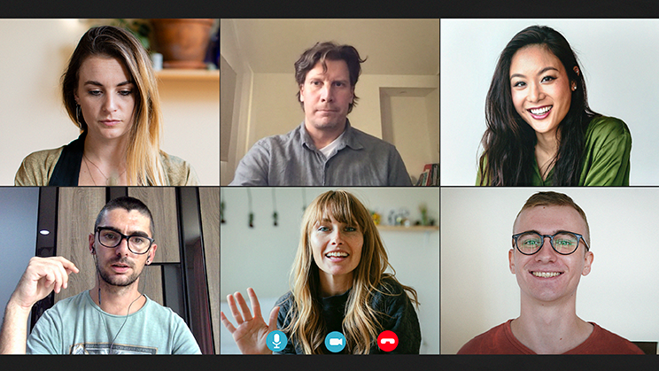Six people in a video conference call. Smiling, talking, and looking at the screen, indoors.