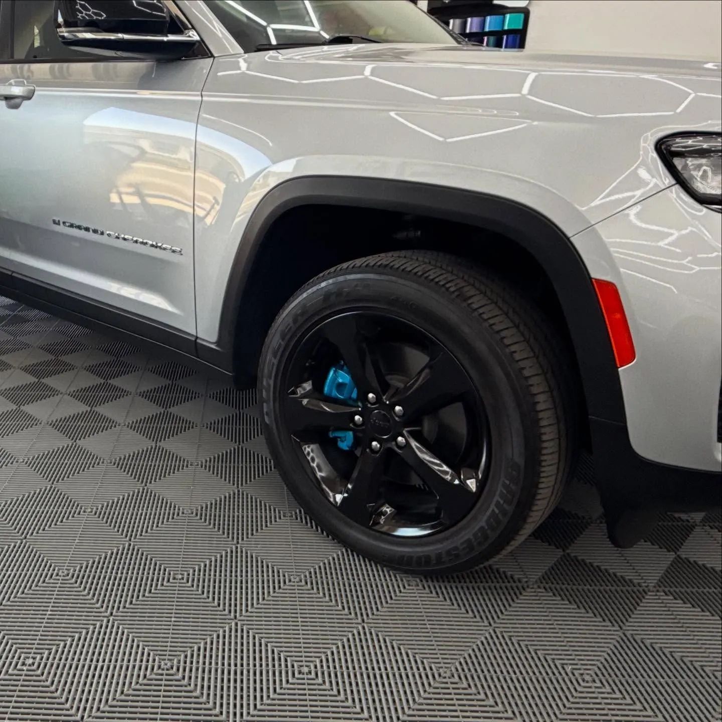 Silver SUV with black wheels parked indoors on a patterned showroom floor