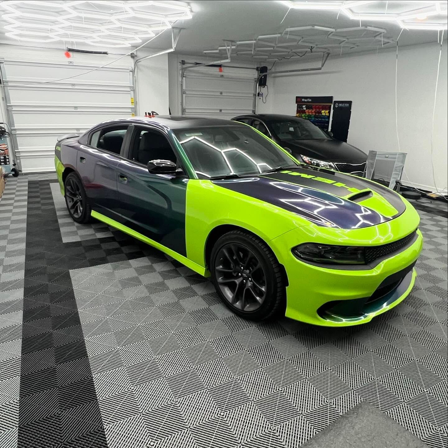 A two-toned Dodge Charger, neon green and dark purple, parked in a garage.