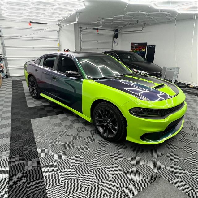Lime green and dark purple Dodge Charger in a garage.