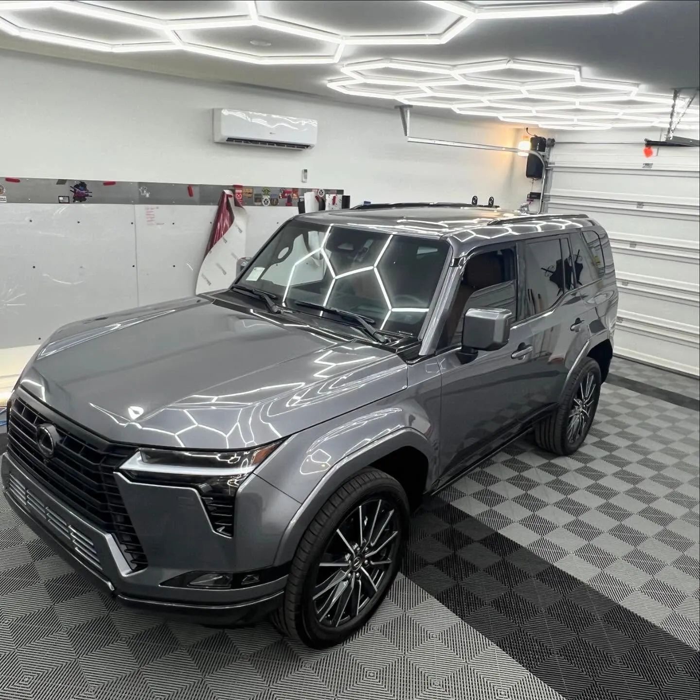 Gray SUV parked in a modern garage with hexagon ceiling lights and patterned floor mats