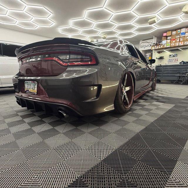 Gray and maroon Dodge Charger on tiled floor, low rider with red accents, under hexagon lights.
