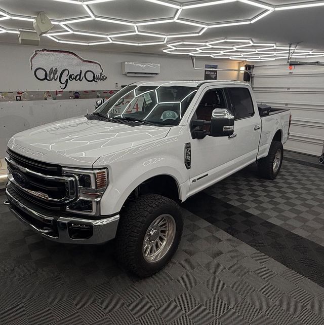 White Ford pickup truck in a well-lit garage with black and gray flooring.