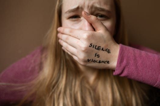 A person covers their mouth with their hand, which has the words 
