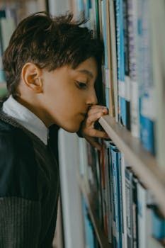 A person resting their forehead and hand against a bookshelf in a library.