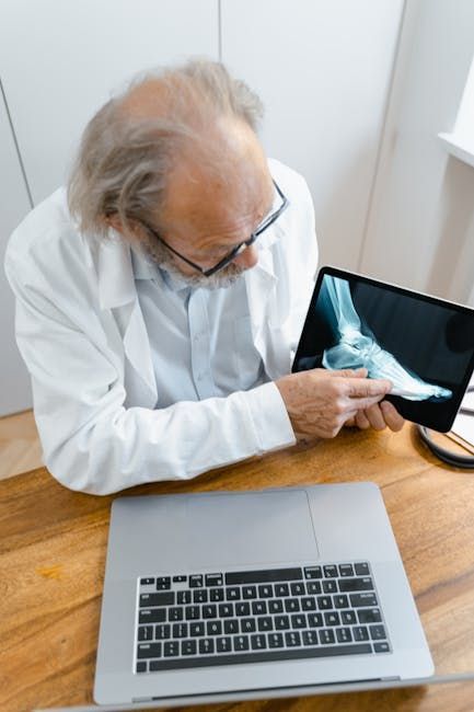 A professional in a lab coat pointing at an X-ray image of a foot displayed on a tablet.