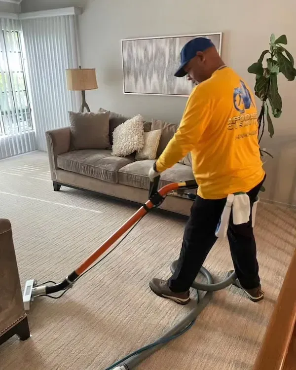 A woman is using a vacuum cleaner to clean a carpet in a living room.