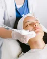 A practitioner uses an ultrasound therapy device with gel on a patient's back during a clinical treatment.