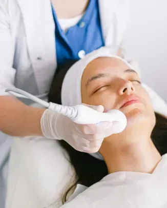 A practitioner uses an ultrasound therapy device with gel on a patient's back during a clinical treatment.