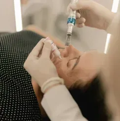 Aesthetic facial injection being administered to a reclining patient in a clinic